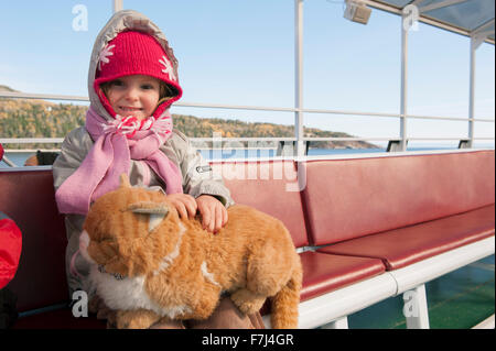 Petite fille assise sur le ferry avec chat en peluche sur ses genoux, portrait Banque D'Images