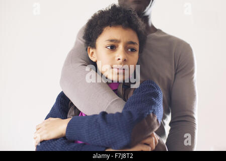 Boy leaning against père avec expression inquiète sur le visage Banque D'Images