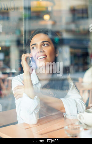 Woman talking on cell phone in coffee shop Banque D'Images