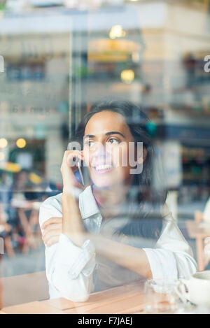 Woman talking on cell phone in coffee shop Banque D'Images