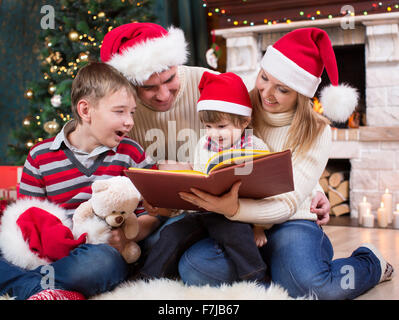 Lire un livre de la famille in front of Christmas Tree Banque D'Images