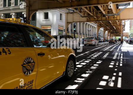 Un taxi jaune sur la rue en bas de puits du sud Chicago L, en viaduc. Banque D'Images