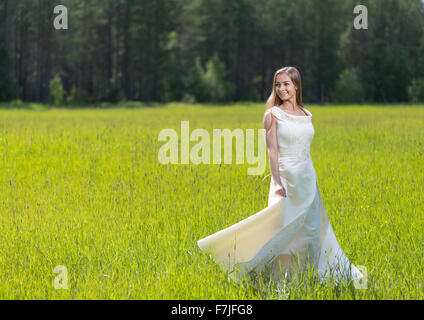 Young smiling woman in white dress standing in field Banque D'Images