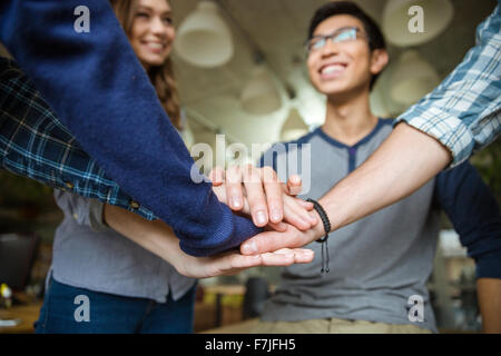 Heureux confiant jeunes collègues poser les mains sur le dessus de l'autre dans le bureau Banque D'Images