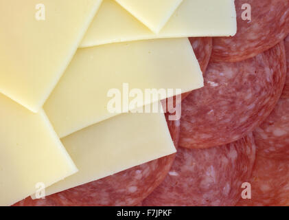 Un gros plan de tranches de salami de Gênes et de fromage provolone illuminé par la lumière naturelle. Banque D'Images