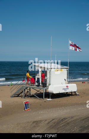 Soleil de l'été, ciel bleu et mer, Sandsend, côte du Yorkshire, England, UK - rivage est calme, drapeau de la RNLI est aux commandes et de sauveteurs patrouillent la plage. Banque D'Images