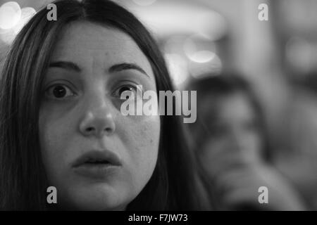 Jeune femme avec surprise / air soucieux fixant l'appareil photo avec arrière-plan flou en noir et blanc Banque D'Images