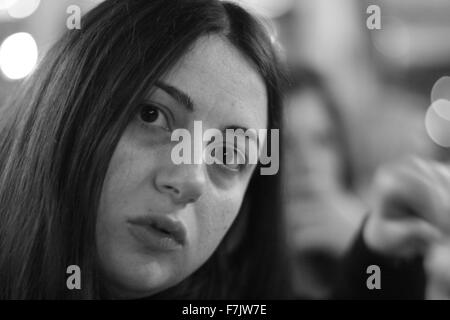 Jeune femme avec un regard inexpressif à regarder l'appareil photo avec arrière-plan flou en noir et blanc Banque D'Images