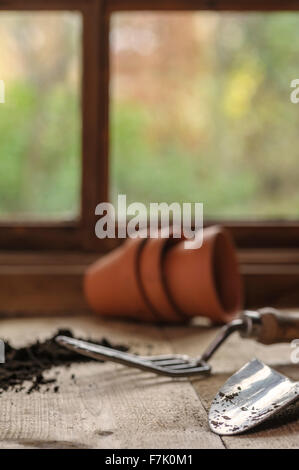 Trois pots en terre cuite sur un banc d'empotage, avec la fourche et truelle. Banque D'Images