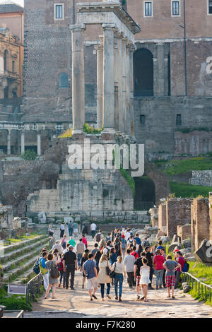 Rome, Italie. Les visiteurs dans le Forum Romain à marcher vers les ruines du temple de Saturne. Banque D'Images