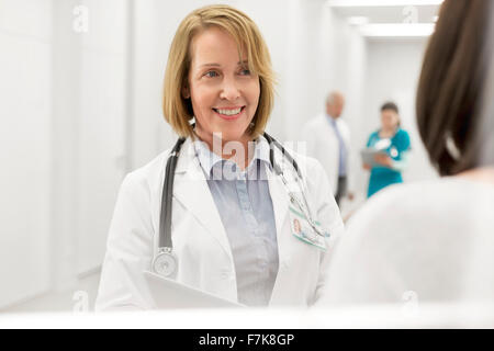 Smiling doctor talking to patient in hospital corridor Banque D'Images