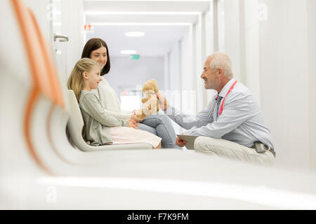 Médecin avec ours parlant à la fille dans le couloir de la clinique du patient Banque D'Images