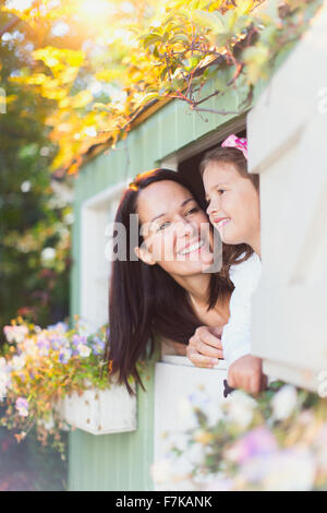 Smiling mother and daughter dans fenêtre playhouse Banque D'Images