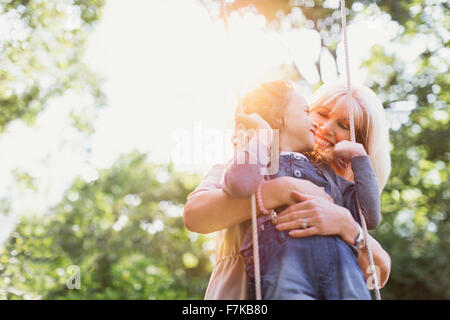 Grand-mère hugging granddaughter on swing Banque D'Images