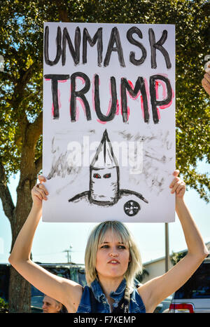 Une jolie jeune femme manifestant est titulaire d'un signe fait main avec caractère KKK lit démasquer à l'atout de Donald Trump rassemblement politique Banque D'Images