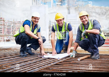 Portrait confiant aux travailleurs de la construction et de l'examen d'ingénieur plan at construction site Banque D'Images