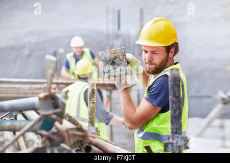 Construction Worker carrying metal bar at construction site Banque D'Images