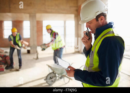 Foreman with digital tablet à l'aide de talkie-walkie at construction site Banque D'Images