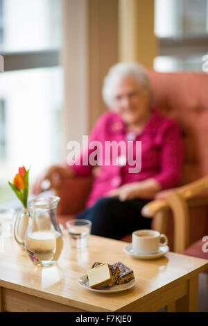 Une vieille dame ayant une tasse de thé dans un old folks home Banque D'Images