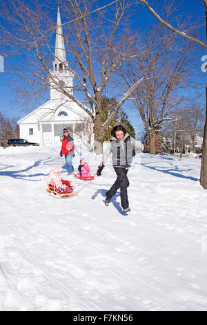 Tire le traîneau du Père fille dans la neige en face de l'église de la Nouvelle Angleterre, dans la ville de Harvard, MA., New England, USA Banque D'Images