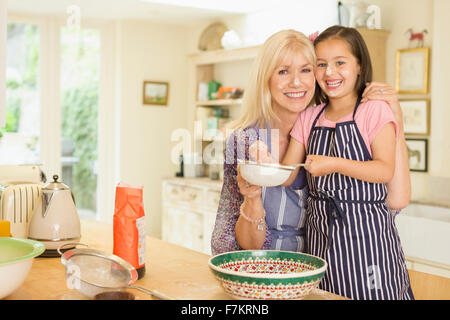 Portrait smiling grandmother and granddaughter baking in kitchen Banque D'Images