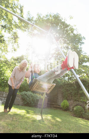 Grand-mère-fille insouciante poussant sur swing in backyard Banque D'Images