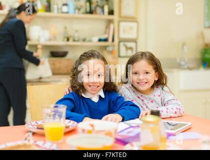 Portrait smiling sisters à table de petit déjeuner Banque D'Images