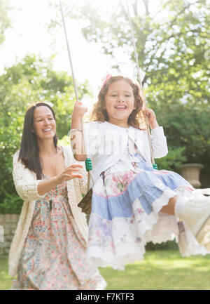 Robe fille mère en poussant sur swing in backyard Banque D'Images