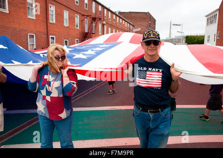 Les gens tiennent pour drapeau américain géant bicentenaire de la guerre de 1812 qui a aussi des espaces pour l et drapeau britannique, USS Constitution Museum, et navire Freedom Trail, Boston, MA Banque D'Images