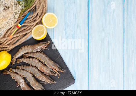 Matières premières fraîches crevettes géantes et du matériel de pêche sur la table en bois. Top View with copy space Banque D'Images