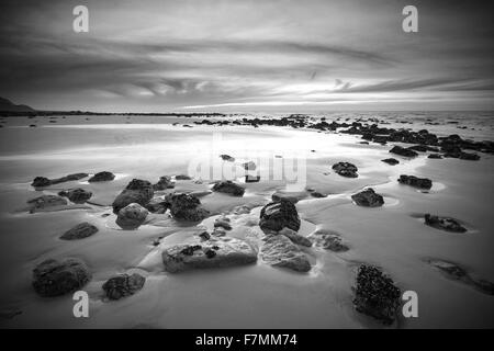 Lever du soleil sur la plage de sable du paysage rocheux avec de ciel et nuages en noir et blanc Banque D'Images