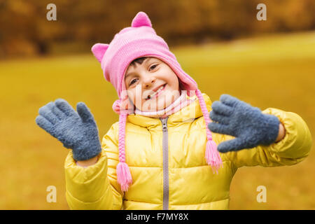 Happy little girl waving hands outdoors Banque D'Images