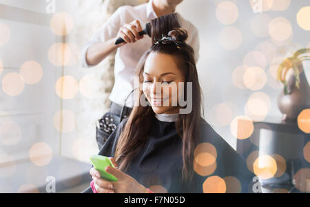 Femme heureuse avec des décisions au salon de coiffure styliste Banque D'Images