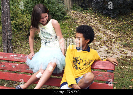 Les jeunes amis ensemble sur banc de parc Banque D'Images