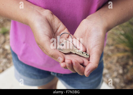 Girl holding key en creux des mains, cropped Banque D'Images