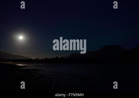 Pleine lune rivière paysage de nuit entouré de montagnes Banque D'Images