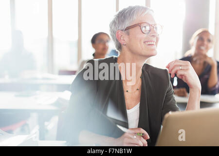 Smiling senior woman at laptop en classe d'éducation des adultes Banque D'Images