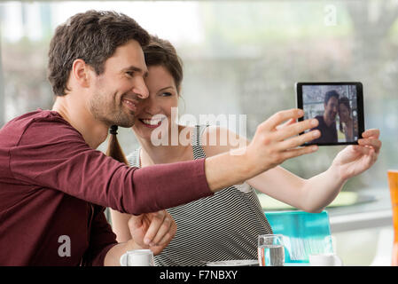 Couple smiling pour prises selfies with digital tablet Banque D'Images