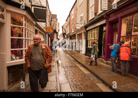 Recherche le long de la pagaille, une étroite rue pavée, à York, North Yorkshire, Angleterre occupé avec les consommateurs et les touristes Banque D'Images