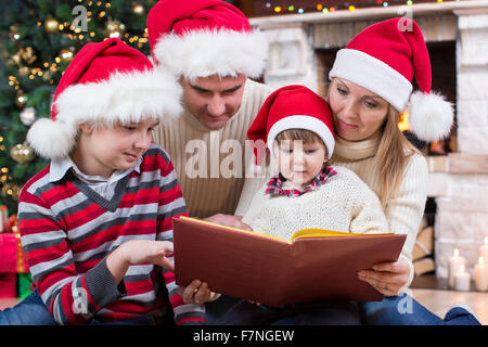 Lire un livre de la famille in front of Christmas Tree Banque D'Images