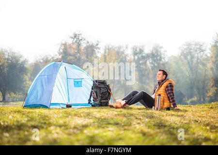 Camping-jeunes hommes assis sur l'herbe dans un champ à côté de la tente d'un regardant le ciel Banque D'Images