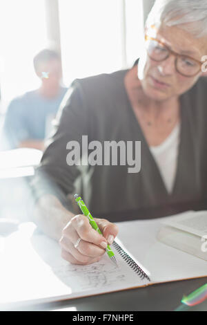 Senior woman faire leurs devoirs en classe d'éducation des adultes Banque D'Images