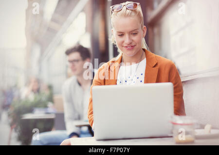 Woman using laptop at sidewalk cafe Banque D'Images