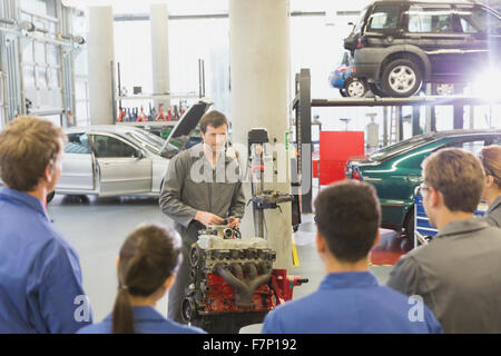 Moteur de voiture mécanicien expliquant aux étudiants en atelier de réparation automobile Banque D'Images