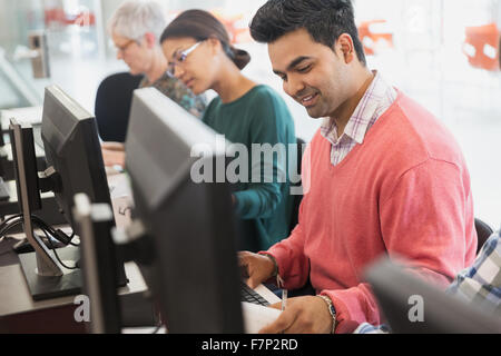 Smiling l'éducation des adultes étudiant à l'ordinateur en classe Banque D'Images