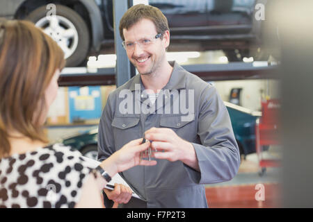 Les clés de la prise de mécanicien femme in auto repair shop Banque D'Images