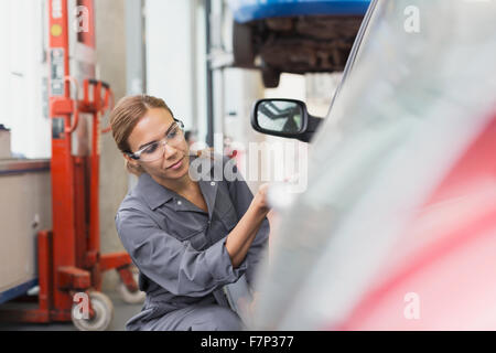 L'examen de mécanicien femelle en voiture auto repair shop Banque D'Images