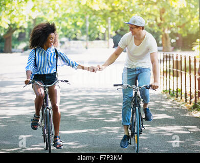 Couple riding bicycles in urban park Banque D'Images