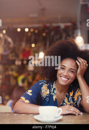 Portrait of smiling woman drinking coffee in cafe afro