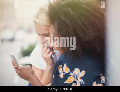 Laughing friends texting with cell phone Banque D'Images